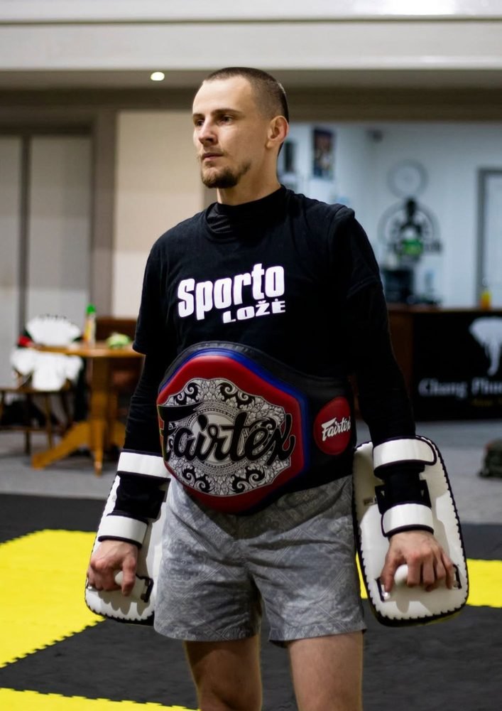 Fighter holding a championship belt in a Sports Lodge shirt