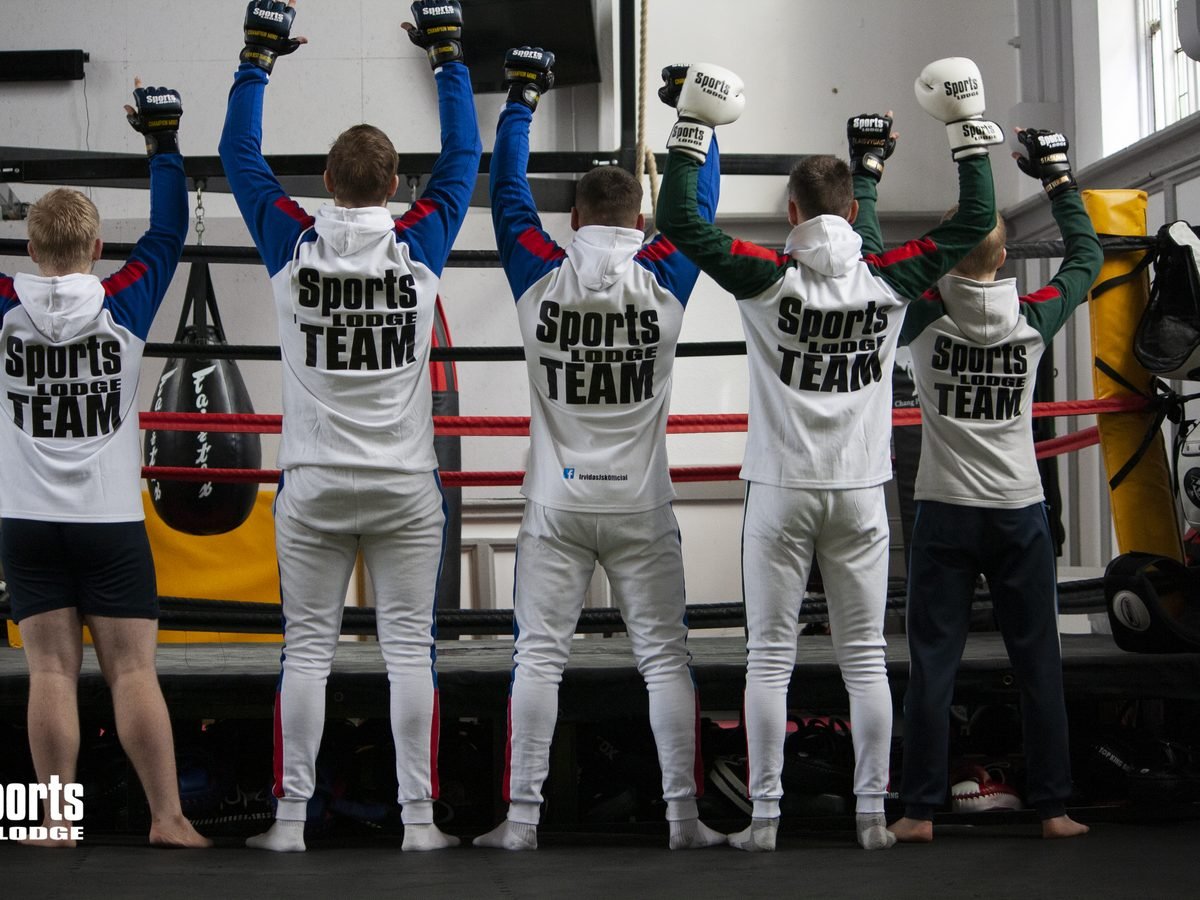 Five athletes in Sports Lodge Team jackets raising boxing gloves