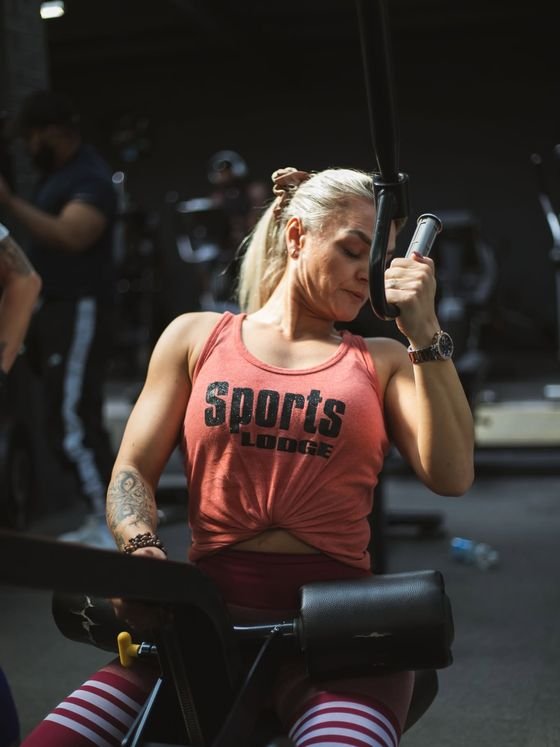 Personal trainer in a Sports Lodge vest training on a gym machine